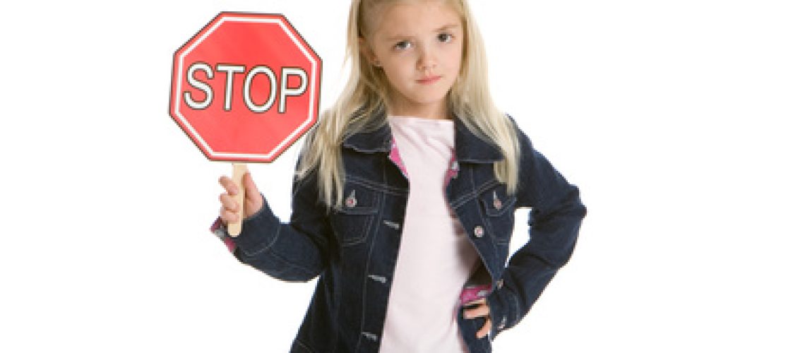 Cute little girl holding a stop sign on white background